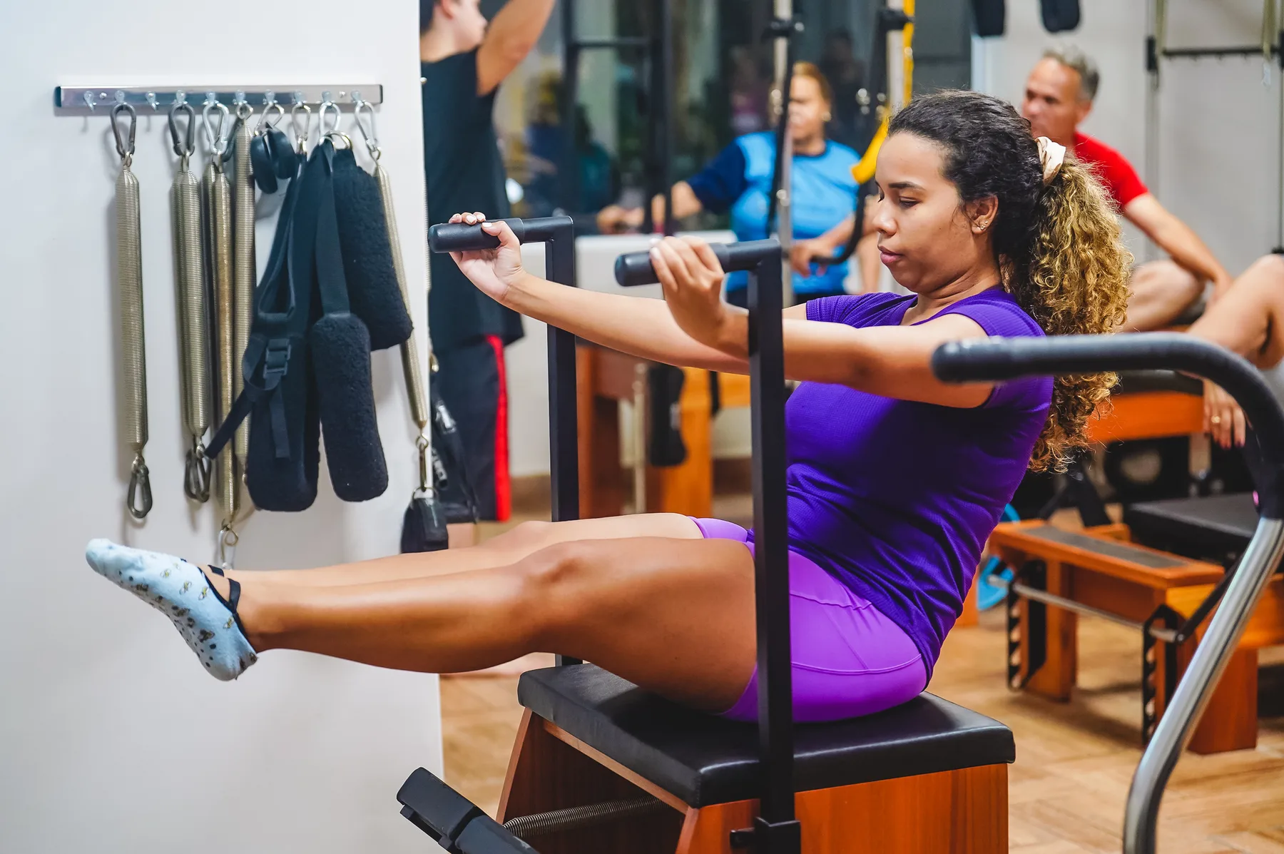 Aluna praticando exercício de Pilates em equipamento reformer, demonstrando postura correta e alinhamento